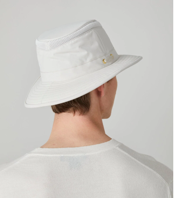 A man shown from the back wearing a white wide-brim bucket hat with a mesh back panel and small gold-tone hardware, against a plain light gray studio background.