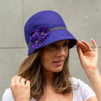 A woman wearing a purple wool felt cloche hat with a fine polka dot trim.